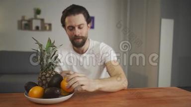一个年轻人坐在桌子旁，谈论<strong>水果</strong>的用处，他拿起<strong>水果</strong>，<strong>展</strong>示菠萝、鳄梨